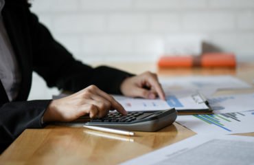 Start up business concepts,Accounting staff is summarizing the company budget.She uses a calculator and analyzes the data graph,Accounting concept